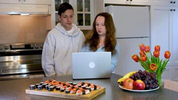 aussehen beim Laptop lehnen Über konzentriert denken aussehen Jugendliche tun Hausaufgaben im das Küche bestellt Sushi Treffen nach Schule zuerst Datum Uhr Film verbringen Zeit zusammen Junge Mädchen 13 14 15 Jahre alt video