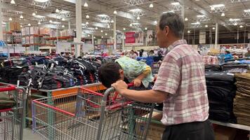 Costco Wholesale Shopping cart asian man with a boy in a shopping cart child playing sitting rolling baby clothes shopping shopping sellers and people choosing video