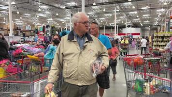 costco grossist- handla i en enorm mataffär människor gående förbi med kärror välja varor hög tak i de Lagra annorlunda mat på de disken rusa kvinnor och män grossist- Amerika kanada video