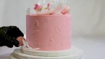 decoratie van een taart voor een familie doop roze taart met voetafdrukken van klein kind Aan top van engel Vleugels en baby in roze luier een meisje hoe naar vind uit geslacht van kind met de helpen van een taart video