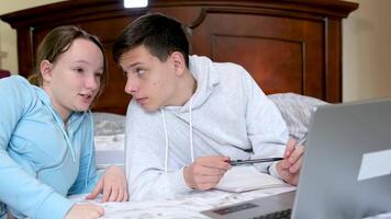 uma menina mostra interessante em formação para uma Adolescência Garoto em uma computador portátil sorridente a Garoto deram flores primeiro amor relação dentro adolescência ampla janela brilhante quarto sentar dentro quarto em cama dentro fato de treino jeans video