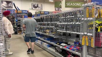 racks with variety of goods customers buyers between rows slow motion filming store inside Princess Auto Ltd. Canadian retail chain specializing in farm, industrial, garage, hydraulics surplus items. video