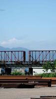 Pattullo Bridge over Fraser River train passing under bridge. close-up shot from technological site scattered iron beams for the construction of new bridge against the backdrop of mountains and sky video