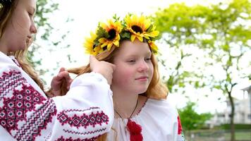 girl are sitting in park waiting for holiday to weave hair braid pigtail wreaths of flowers on head help friend tenderness beauty young hairdresser young women are preparing for celebration video