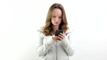 porträtt av spänd koncentrerad kvinna tonåring med mycket lång brun hår spelar spel på henne cell telefon varelse vinnare gestikulerar i glädje över vit bakgrund. begrepp av känslor video