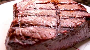 grillé t-bone steak servi sur blanc assiette dans Viande restaurant, filmé de au dessus avec Zoom en dehors effet.close en haut agrafe de du boeuf pièce grillé avec poivre, romarin pimenter pour dîner repas dans le dîner café video