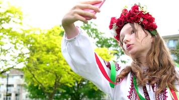 Ukrainian woman in a traditional folk image looks at the phone taking a selfie Looks in the mirror wreath white flowers beauty of a teenager girl Ukraine No war joy nature Tenderness social networks video