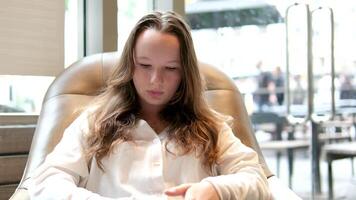 encantador mulher com lindo sorrir lendo Boa notícia em Móvel telefone durante descansar dentro café comprar, feliz caucasiano fêmea assistindo dela fotos em célula Telefone enquanto relaxante dentro cafeteria durante livre Tempo video