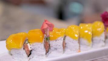 detailopname, mango sushi reeks Aan wit klei bord wit achtergrond mango en room kaas sushi smaak video