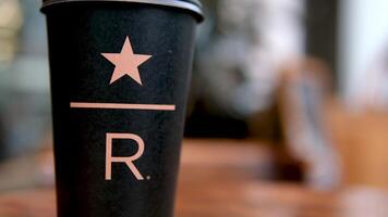Starbucks Resort black Starbucks cup with star underline big letter R on the table in the coffee shop delicious new coffee luxury famous brand newest video