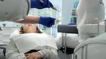 senast teknologi rengöring och blekning tänder sjuksköterska och läkare behandla tänder av kvinna patient tonåring. senast enhet i en dental kontor i en klinik tar vård av tänder Snövit leende video
