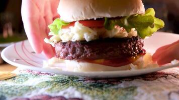 mit beide Hände nehmen das Burger von das Teller bekommen bereit zu Essen Abendessen wählen oben das Burger mit das Küche Schnitzel mit Mozzarella Käse Tomate Salat video