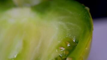 lento movimiento Disparo de grande amarillo y verde Tomates siendo lavado o salpicado con lluvia, en parte superior de un blanco superficie video