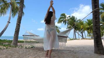 bailando en el playa costoso hotel viaje anuncio elegante lujo playa joven mujer niña en un blanco pareo negro traje de baño bailes en el mar Oceano video