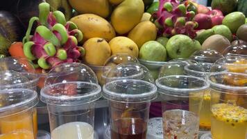 fruta sucos noite mercado fechar acima tiroteio do variado sortimento do fresco frutas dentro plástico copos às a local noite mercado. tailândia, pattaya. video