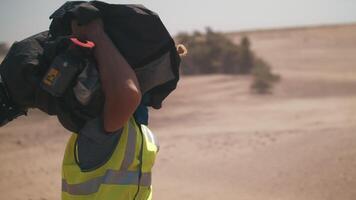 un hombre lleva un película cámara. rodaje en el desierto. tormenta de arena video