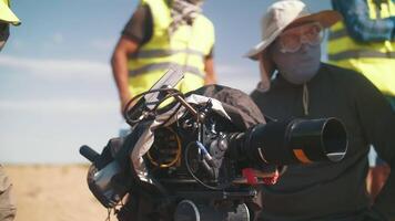 filme equipe técnica protegendo a filme Câmera a partir de uma tempestade de areia. fazer filmes debaixo desafiador condições dentro a vento dentro a deserto video