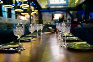 A table with a number of wine glasses and plates. The table is set for a meal. Scene is elegant and sophisticated. photo