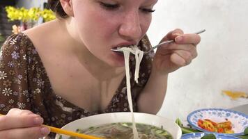 de cerca retrato de joven mujer disfrutar comiendo tallarines en un taza a hogar. basura comida concepto. video