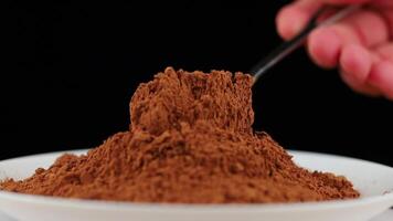 Cocoa powder on a spoon on black close-up video