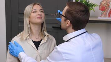 une Jeune attrayant oto-rhino-laryngologiste examiner nez de une Jeune patient pendant une médical examen dans le ent Bureau video