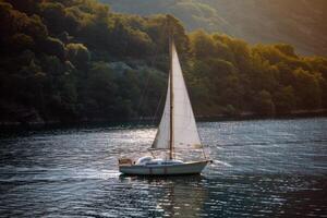 Sailboat drifting lazily on calm lake, its sails billowing in the gentle summer breeze photo