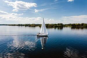 Sailboat drifting lazily on calm lake, its sails billowing in the gentle summer breeze photo