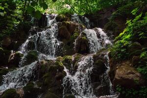 Majestic waterfall cascading down moss-covered rocks into refreshing pool below photo