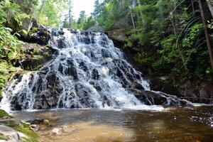 Majestic waterfall cascading down moss-covered rocks into refreshing pool below photo