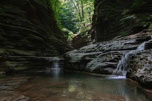 majestuoso cascada cascada abajo cubierto de musgo rocas dentro refrescante piscina abajo foto