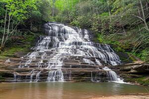 majestuoso cascada cascada abajo cubierto de musgo rocas dentro refrescante piscina abajo foto