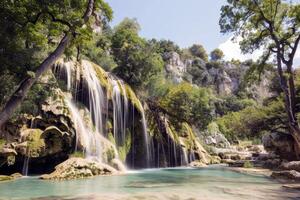 majestuoso cascada cascada abajo cubierto de musgo rocas dentro refrescante piscina abajo foto