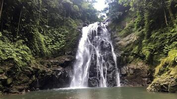 Majestic waterfall cascading down moss-covered rocks into refreshing pool below photo