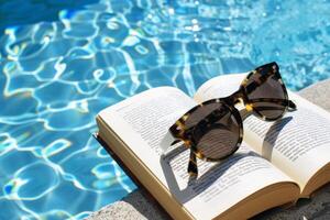 Pair of sunglasses resting on book by the poolside, epitomizing lazy summer days photo