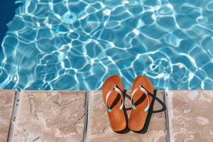 Pair of flip-flops left at the edge of pool, signaling carefree summer day photo