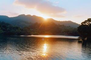 Sunset over tranquil lake, casting warm glow over the water and surrounding landscape photo