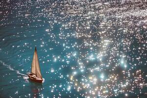 Sailboat gliding across sparkling blue waters, propelled by gentle summer breeze photo