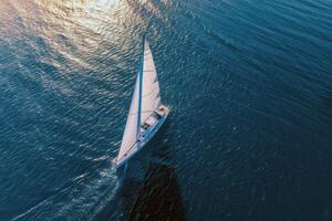 Sailboat gliding across sparkling blue waters, propelled by gentle summer breeze photo