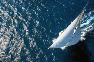 Sailboat gliding across sparkling blue waters, propelled by gentle summer breeze photo