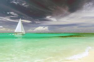 Sailboat gliding across sparkling blue waters, propelled by gentle summer breeze photo