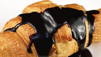 Schokolade gegossen auf Croissant Nahansicht. Schokolade mit ein Croissant auf ein Platte. video
