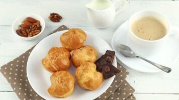Eclairs mit Schokolade, Cappuccino und Milch. Süss Frühstück. Profiteroles mit Sahne video