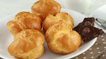 Eclairs with broken chocolate on a white plate. video