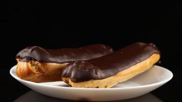 cioccolato eclairs nel un' bianca piatto avvicinamento. video