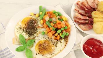 Fried eggs with vegetables, fried bacon and potatoes. Hearty food and a delicious lunch. video