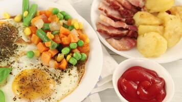 Fried eggs with vegetables, fried bacon and potatoes. Hearty food and a delicious lunch. video