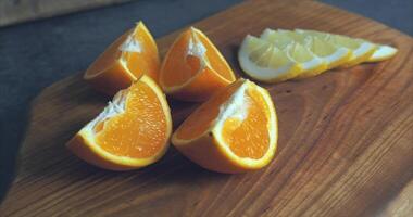 Orange cut into slices and lemon slices lie on a wooden board video