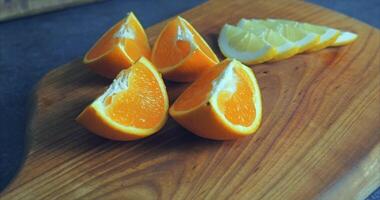 On a wooden board lies a lemon cut into slices and a juicy orange cut into four parts video