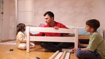 father and children are assembling new furniture, bed at home video