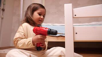 portrait of a little girl tightening a bolt, screw with electric screwdriver video